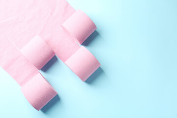 Pink toilet paper rolls on light blue background, top view. Space for text