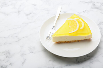 Piece of tasty lemon cheesecake and fork on white marble table, closeup. Space for text