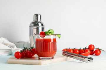 Glass of bloody mary with celery, tomatoes and tongs on white background