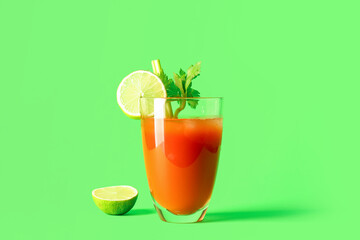 Glass of bloody mary with celery and cut lime on green background