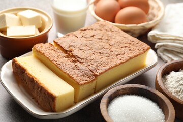 Tasty Japanese Castella sponge cake and ingredients on light table, closeup
