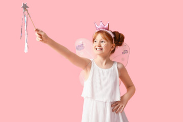 Cute girl in fairy costume playing with magic wand on pink background