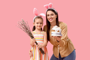 Beautiful young woman in bunny ears with Easter cake and her cute little daughter holding pussy...