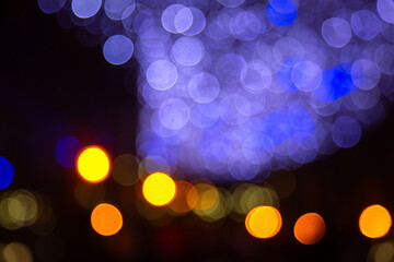 Dreamy bokeh with golden and vibrant light spots on a dark setting, suggesting a festive or romantic ambiance with a blurred, artistic touch.