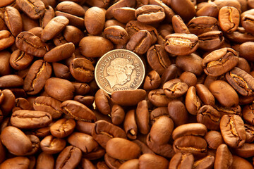 Close-up of roasted coffee beans surrounding a dime on a shiny gold surface, highlighting their earthy tones and natural splits. Ideal for food and beverage photography.