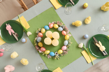 Beautiful table setting with candles, decorative chickens and Easter eggs in dining room