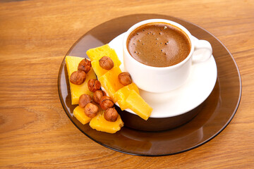 A rustic scene featuring a white cup of bold espresso with a frothy layer, paired with golden cheese slices, displayed on a warm wooden table.
