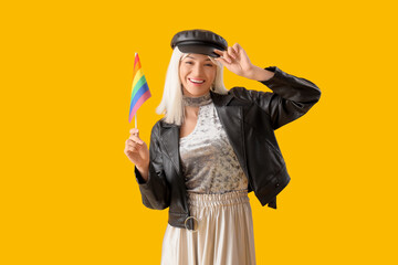 Beautiful young woman with rainbow flag on yellow background. LGBT concept