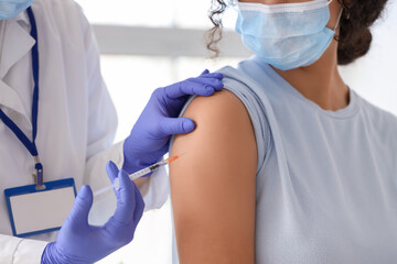 Naklejka premium Female doctor vaccinating young woman in clinic, closeup
