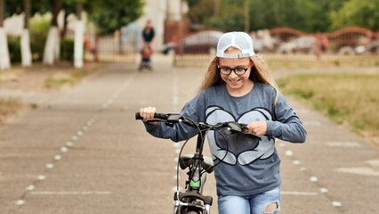 Obraz premium An eleven-year-old girl in a good mood rides a bicycle and after a stop shows a thumbs-up.