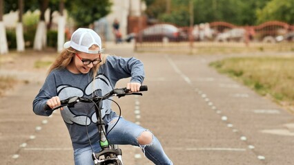 Child blond girl riding a bicycle on a bike path in summer