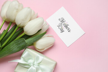 Bouquet of beautiful white tulip flowers with greeting card and gift box on pink background. Mother's Day celebration