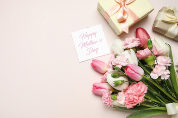 Bouquet of different beautiful flowers with greeting card and gift boxes on beige background. Mother's Day celebration