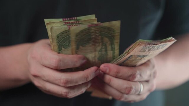 Close-up of a man's hand counting Paraguayan guaran&iacute; bills