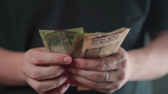 Close-up of a man's hands arranging Paraguayan guaran&iacute; bills