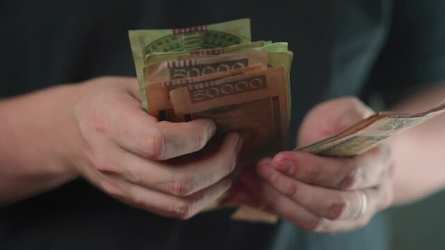 Close-up of a man's hands counting Paraguayan guaran&iacute; bills 2