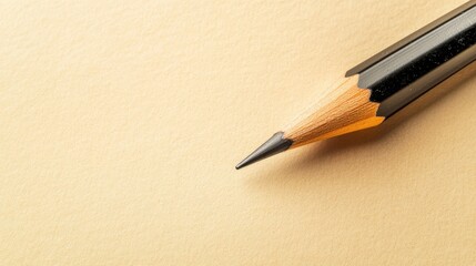 Pencil on Beige Paper: A sharply pointed graphite pencil rests on a beige surface, ready for writing or drawing.  The image is minimalist and clean.