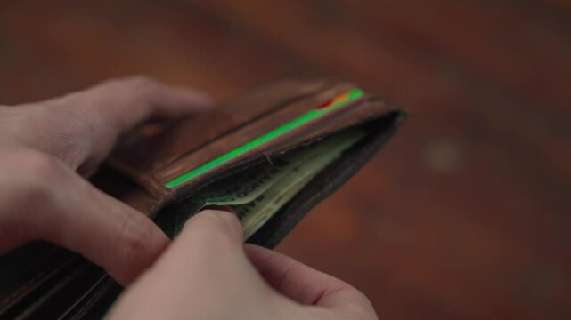Man's hand taking out a one-hundred-thousand guaran&iacute; bill from Paraguay