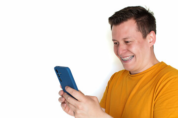 Happy young man with dental braces using mobile phone and smiling on white background