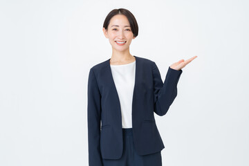 白背景で案内をするスーツを着た女性