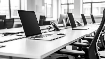 Modern office workspace with laptops and ergonomic chairs in black and white