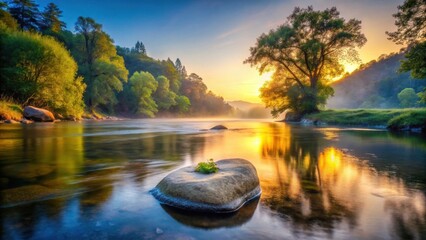 Obraz premium Serene Riverbank Sunrise Tranquil Water Reflecting Golden Light, Lush Foliage, and a Solitary Rock with a Tiny Plant