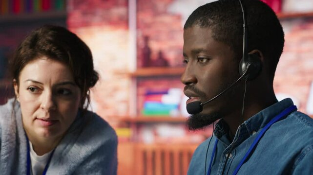 Call center manager doing training for worker providing live chat support, handling clients complaints. Team leader and intern dealing with unsatisfied customers, providing solutions, camera A