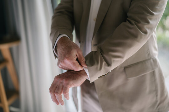 Businessman holding hands with bride during wedding ceremony in a suit.Hands are holding the sleeves of the shirt while putting it on.