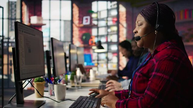 IT support expert at PC in call center office troubleshoots errors to minimize downtime. Tech support agent at desk writing code, maintaining technical systems and infrastructure, camera B