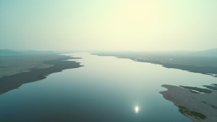 Fototapeta premium Aerial view of winding river delta at sunrise with calm water and soft light 