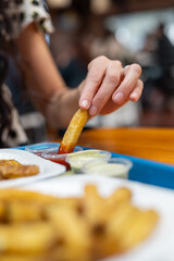 An arm reaches for a crispy fry, dipped in ketchup, capturing the essence of indulgence in a casual dining experience.

