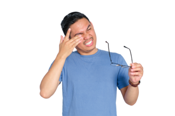 Young Asian man suffering eye discomfort while holding glasses, feeling eye strain or irritation, isolated on transparent background