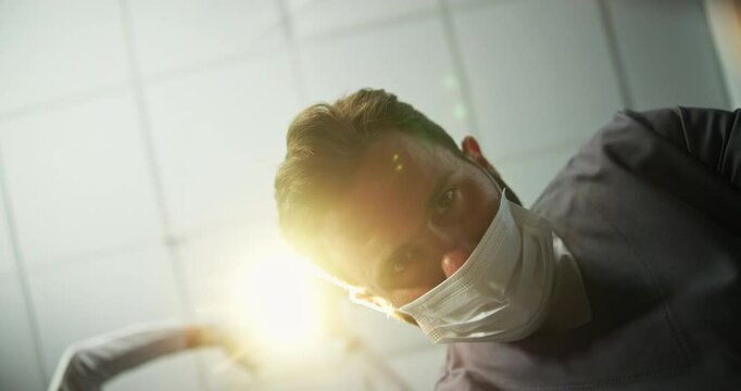 Face, dentist and tools for surgery at clinic with lights, cleaning and teeth whitening for hygiene. Pov, male person and inspection with tooth extraction, root canal and dental implant and procedure