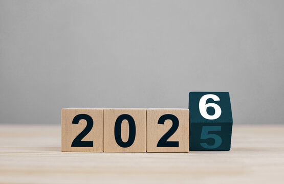 Wood cube with 2025 flips over replaced by the latest 2026 on wooden table background for New Year ideas and goals to get started