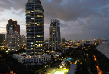 Naklejka premium Miami Beach sunset aerial view. Downtown Miami skyline at dusk. South Beach neon lights at night. Tropical Miami waterfront panorama. Ocean Drive Art Deco buildings. Aerial view of Miami coastline.