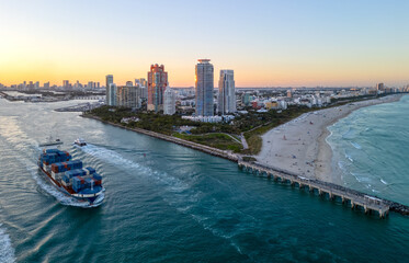 Obraz premium Container Ship in Miami City. Aerial View. Shipping Boat. Cargo ship at Miami harbor. Cargo containers stacked on a ship in Miami. Cargo ship leaving Miami. Cargo vessels from Miamis port.