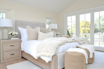 Bright, airy bedroom with neutral tones, large windows, and cozy bedding
