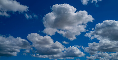 Sun shining through the puffy clouds. Sky view. Beautiful sunny sky. Background with clouds on blue...