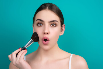 Obraz premium Woman applies powder on the face using makeup brush. Beautiful girl doing contouring apply blush on cheeks. Face beauty cosmetics. Fresh skin and natural make up. Powder blush on facial skin.