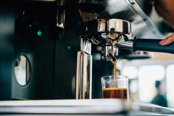 At cafe shop coffee pours from espresso machine. Modern technology showcased with liquid flowing...