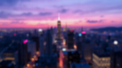 Obraz premium A blurred cityscape at dusk displays silhouetted buildings against a pink and purple sky. City lights softly glow in the distance creating an evening scene.