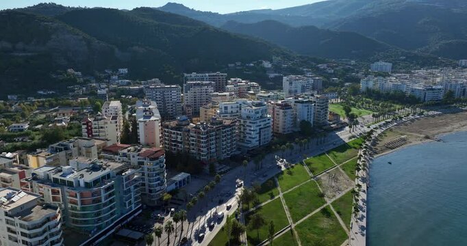 Zoom-out aerial panoramic view of Vlore, Albania. The video captures the city's urban landscape, architecture, coastal area, and surrounding mountains.