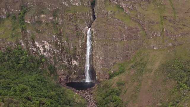 Tall waterfall flowing into dark pool in Serra da Canastra, Brazil, aerial view