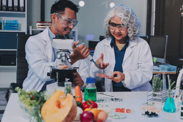 Team Asian scientists in a lab conducting food research using a microscope and lab equipment,...