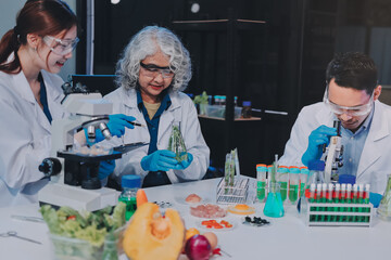 Team Asian scientists in a lab conducting food research using a microscope and lab equipment,...