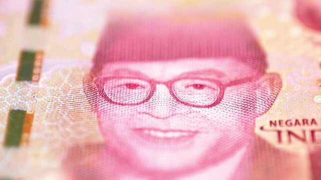 Macro footage captures a detailed view of Dr. Hatta's portrait on the 100,000 Rupiah banknote, showcasing the intricate design and vibrant colors. The angle emphasizes the texture