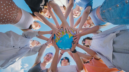 Students holding a globe, symbolizing global citizenship, environmental awareness, and...