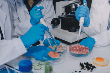 Team Asian scientists in a lab conducting food research using a microscope and lab equipment,...
