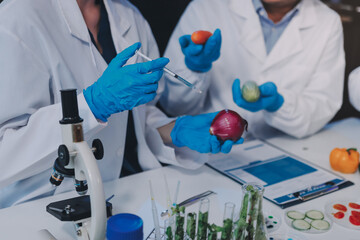 Team Asian scientists in a lab conducting food research using a microscope and lab equipment,...