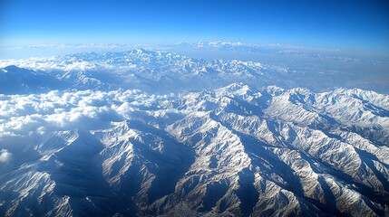 Stunning aerial view of snow-capped mountains under a bright blue sky creating a serene landscape. Perfect for travel brochures or nature documentaries.